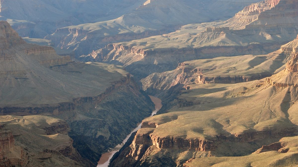 Vista panorâmica do Grand Canyon, Estados Unidos, com camadas rochosas e céu aberto; paisagem natural emblemática de road trips e parques nacionais.